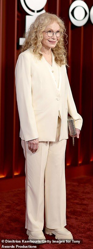 The 80-year-old actress beamed while glammed up in a cream-colored, three-piece white pantsuit with matching platform boots and a golden clutch purse