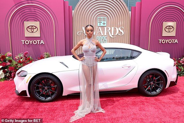 Here she is seen in a power pose in front of a white sports car