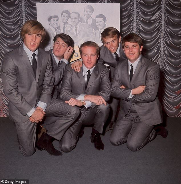 Al Jardine is speaking out following the death of his longtime confidante and collaborator Brian Wilson at 82. The Beach Boys pose in front of an earlier group portrait in 1964 in London. (L-R) Dennis Wilson (1944 - 1983), Brian Wilson, Mike Love, Al Jard