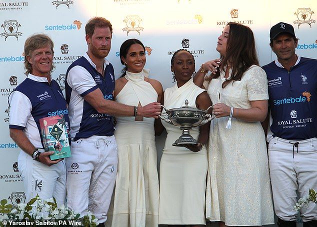 Harry and Meghan with the chair of Sentebale Dr Sophie Chandauka at a charity polo match.Meghan disrupted the Sentebale charity polo match in Spring last year when she turned up alongside tennis legend Serena Williams