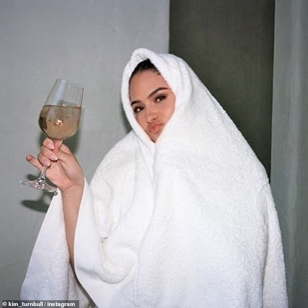 In contrast to the revealing campaign snaps, one picture saw Kim covered up entirely by a fluffy white towel wrapped around her head, while she celebrated with a glass of wine