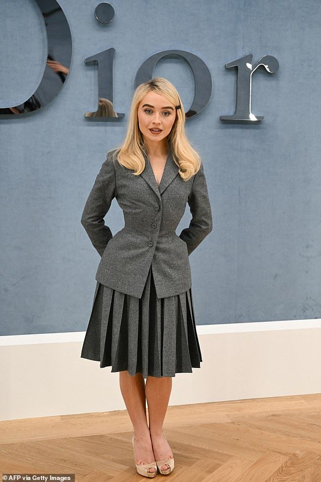 Sabrina Carpenter looked uncharacteristically conservative in a grey pleated skirt suit at the star-studded Dior Homme Menswear during Paris Fashion Week on Friday