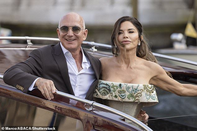 The off-the-shoulder figure hugging gown was embroidered with designs of swirling vines and florals in blue, green, and gold tones that were set against a champagne fabric