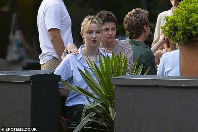 Emma, who dressed casually in a striped T-shirt, placed their hands on a friends shoulders as they chatted