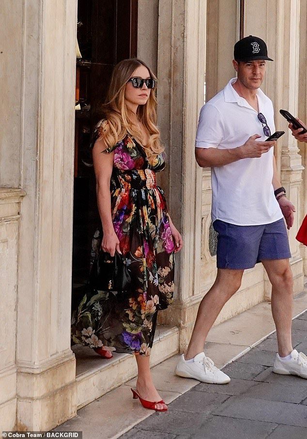 Wearing her blonde locks down, Sydney slipped into a floral dress for the morning stroll before adding a few inches to her frame in a pair of red high heels