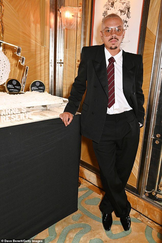 Evan cut a suave figure in a black suit and a red tie as he posed alongside a display ofArne's Reserve Caviar