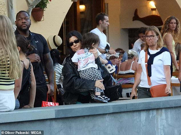 Kourtney easily navigated the cobbled streets in a pair of flip flops, and shielded her eyes with black sunglasses