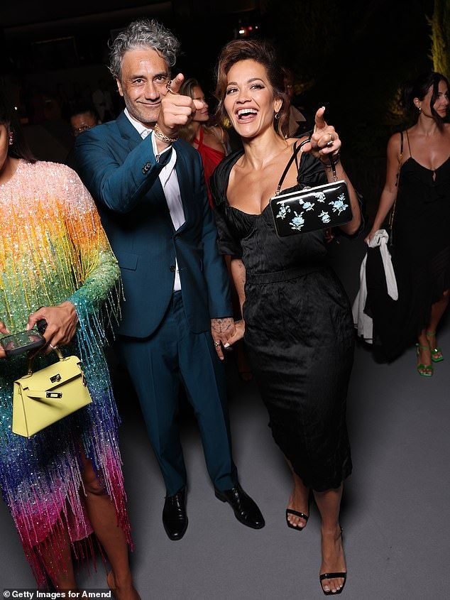 Rita's husbandTaika Waititi looked dapper in a teal blazer and matching trousers along with a white shirt