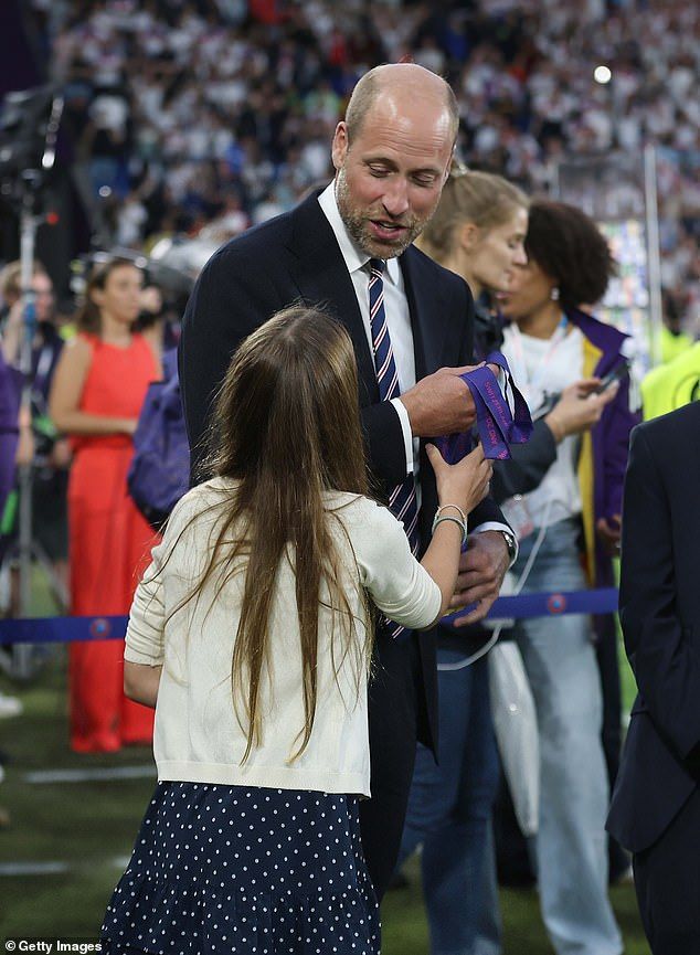In one image, an amused William looks down at his daughter, who reaches out to touch the medals. In fact, the father seems almost to have to hold them back from Charlotte, whose excitement at the Lionesses' win clearly just could not be contained (picture