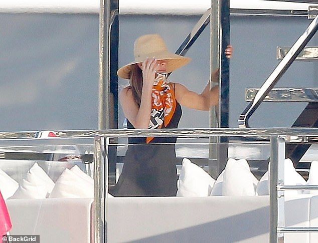 Fashion designer Victoria shielded her face from the bright sunshine with a wide-brimmed straw hat