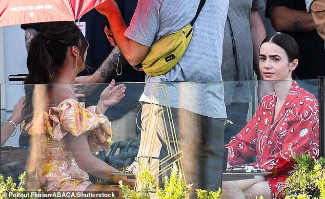 Ashley looked equally as stunning as her co-star as she filmed with a bright coral and pink mini dress that featured huge puffy sleeves