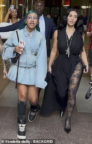 Pairing the floaty black dress with a pair of floral lace tights, the reality star completed her look with black heels and a long silver necklace