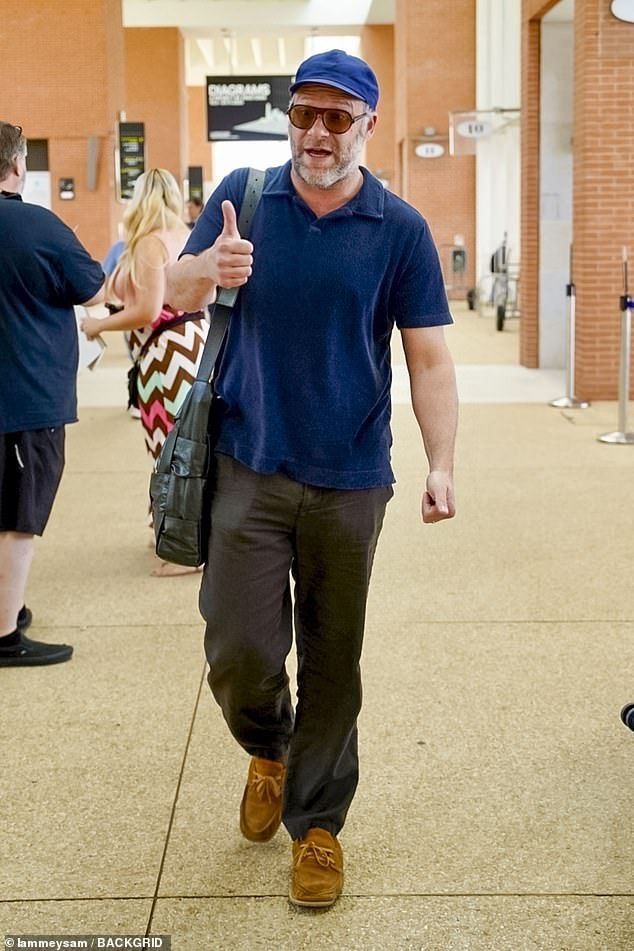 Seth Rogen opted for a navy polo shirt and matching baseball cap before adding a Bottega Veneta bag