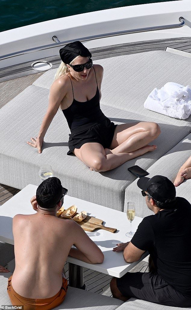 The artist looked slender in a sleek black swimsuit with a black scarf on her head as she worked on her late summer tan