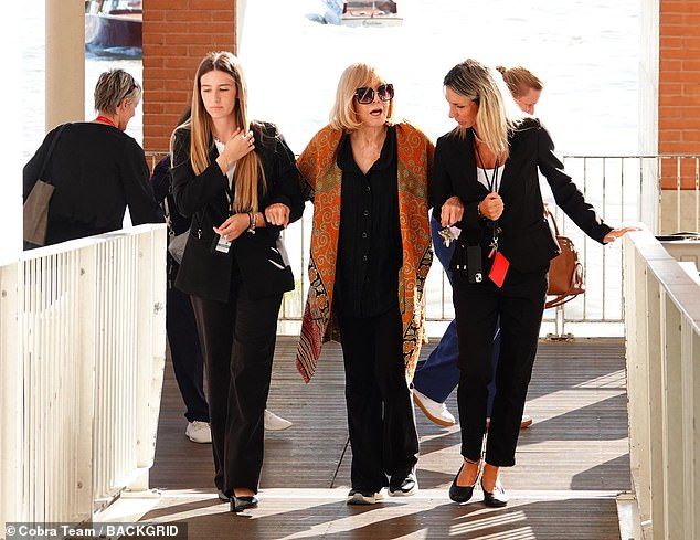 Kim linked arms with two female workers at Venice airport as she headed onto her next destination following a brief trip to collect herGolden Lion for lifetime achievement award