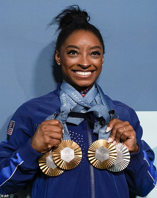 Biles has cemented her legacy as the GOAT with 37 combined Olympic and World Championship medals - the most in gymnastics history (Pictured: Simone Biles holding up her medals at the 2024 Paris Olympics)
