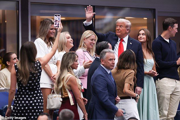 Trump's glamorous assistant and communications advisor, Margo Martin, is seen here (left) in a polka dot dress, righteously doing her job - capturing clips of the president in the box