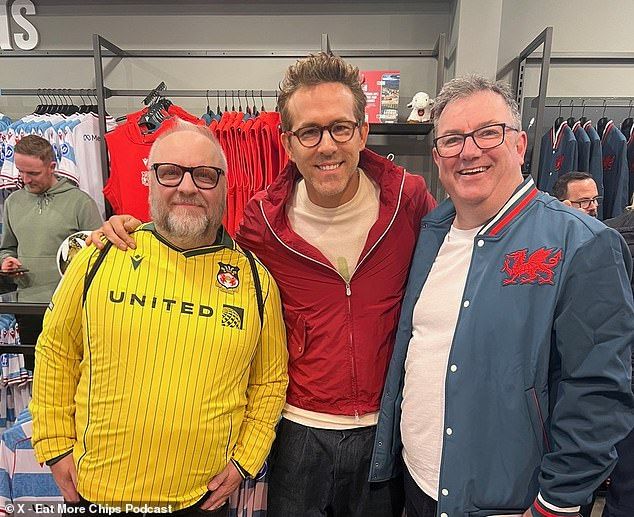 Reynolds (middle) posed with two Wrexham supporters after making the trip to Wales