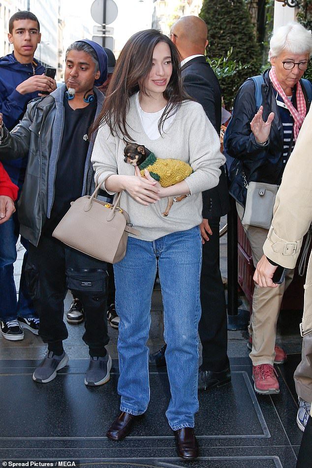Mikeypaired the ensemble with blue denim slim-fit jeans and brown leather boots, strolling along with her pup in her arms